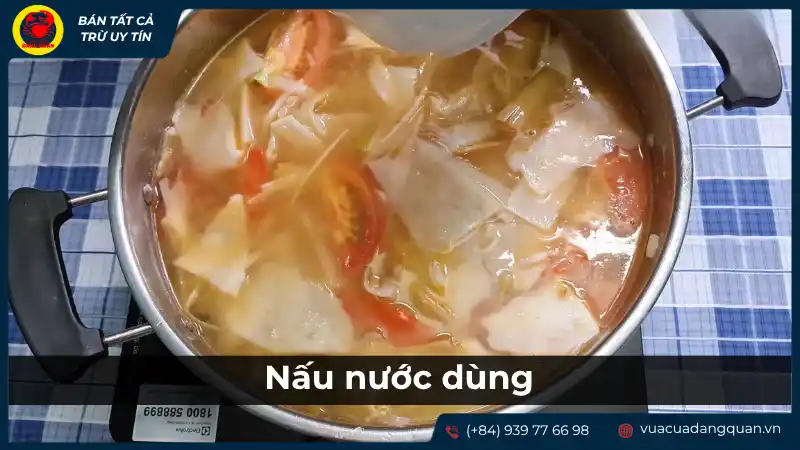 Nồi nước dùng lẩu cá mú măng chua đang được đun sôi, với các nguyên liệu như cá, măng, và có thể là xương ống để tạo vị ngọt.
